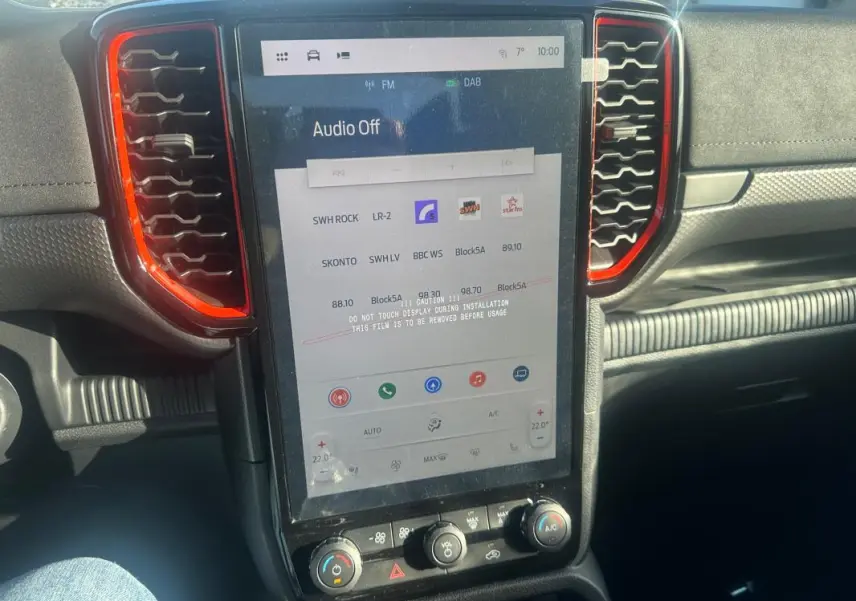 Vue rapprochée de l’écran tactile central du Ford Ranger Raptor 2025 avec entourage d’aération rouge et tableau de bord noir.