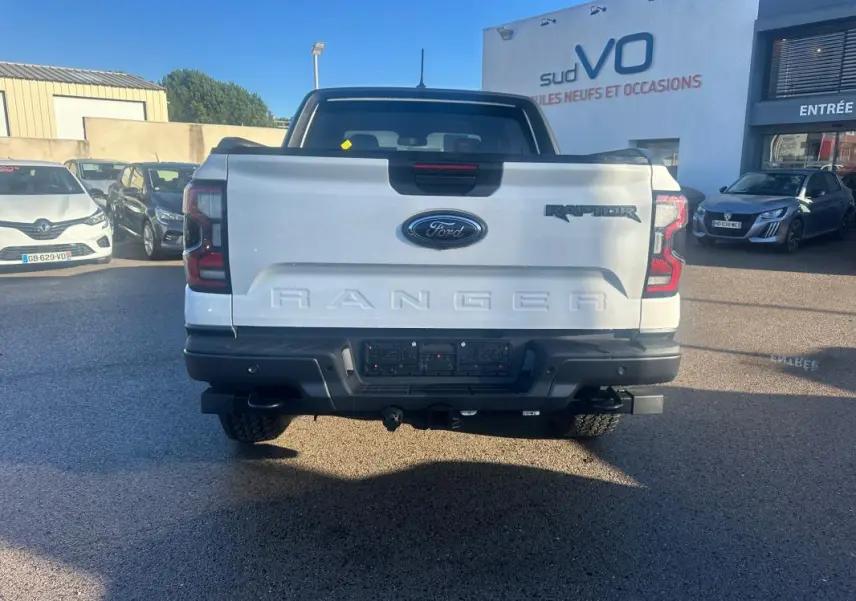 Vue arrière d'un Ford Ranger Raptor blanc 2025 avec hayon marqué Ranger et feux arrière LED distinctifs.
