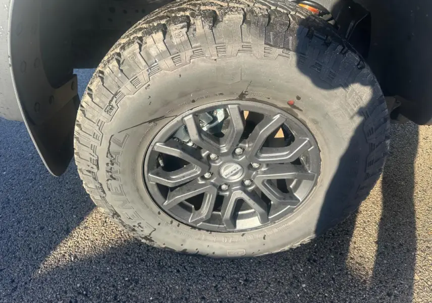 Gros plan sur la roue avant droite du Ford Ranger blanc, jante alliage noire avec pneu tout-terrain.