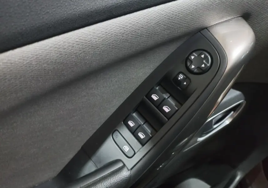 Gros plan sur la commande des vitres électriques côté conducteur d’un Citroën Grand C4 Spacetourer noir, intérieur tissu gris.