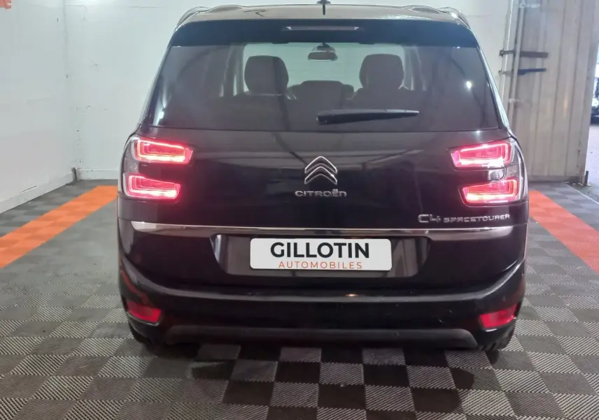 Vue arrière d'un Citroën Grand C4 Spacetourer noir avec feux arrière allumés dans un garage.