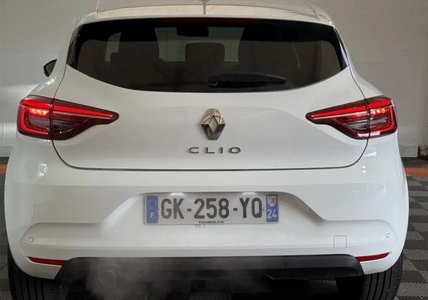 Vue arrière d'une Renault Clio blanche avec feux LED allumés et plaque d'immatriculation française visible.