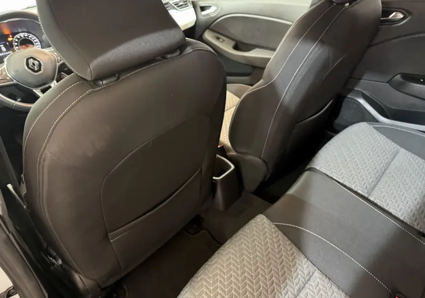 Vue intérieure arrière droite de la Renault Clio Business blanche, sièges tissu gris et noir avec surpiqûres blanches.