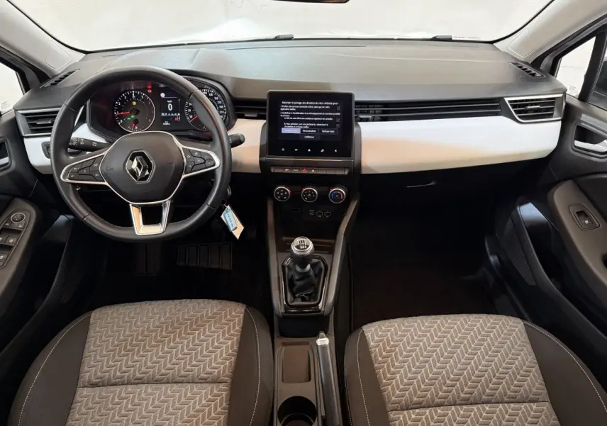 Vue intérieure avant de la Renault Clio Business TCe 100 GPL 2022, volant cuir, écran tactile central et sièges tissu gris.