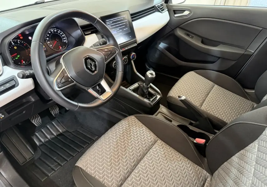 Vue intérieure côté conducteur de la Renault Clio Business TCe 100 GPL 2022, volant cuir, écran tactile et sièges gris à motifs.