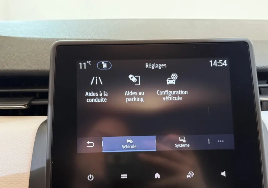 Écran tactile central de la Renault Clio Business blanc, affichant les réglages d’aides à la conduite et parking.
