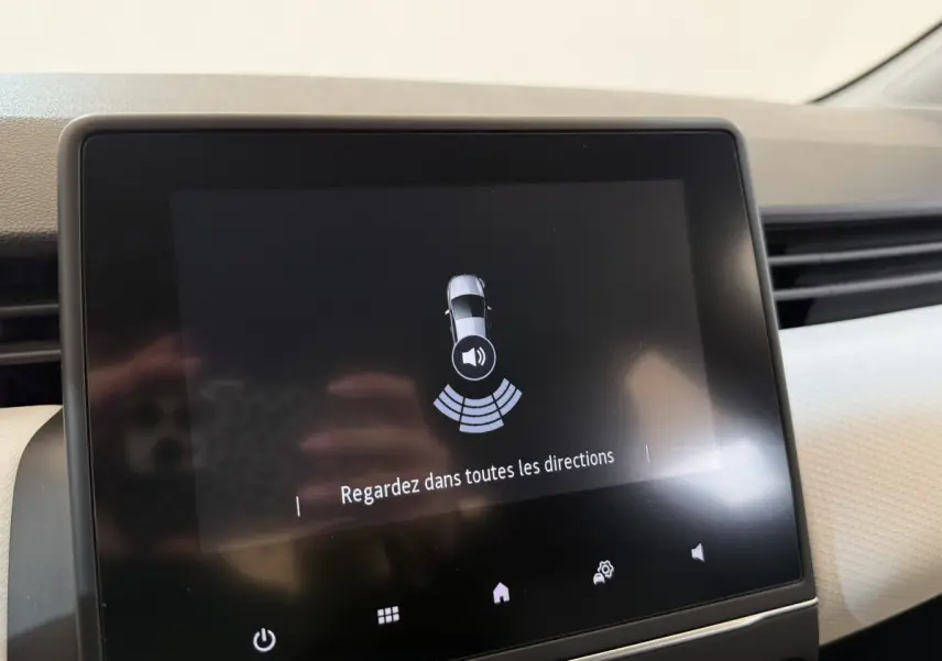 Écran tactile central de la Renault Clio Business blanc, affichant l'alerte de détection d'obstacles au stationnement.