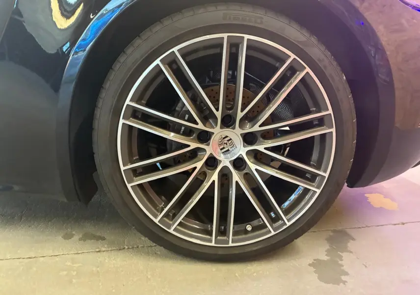 Gros plan sur la roue avant gauche noire d'une Porsche 718 Boxster 2.0 300, avec jante alliage multibranches argentée.