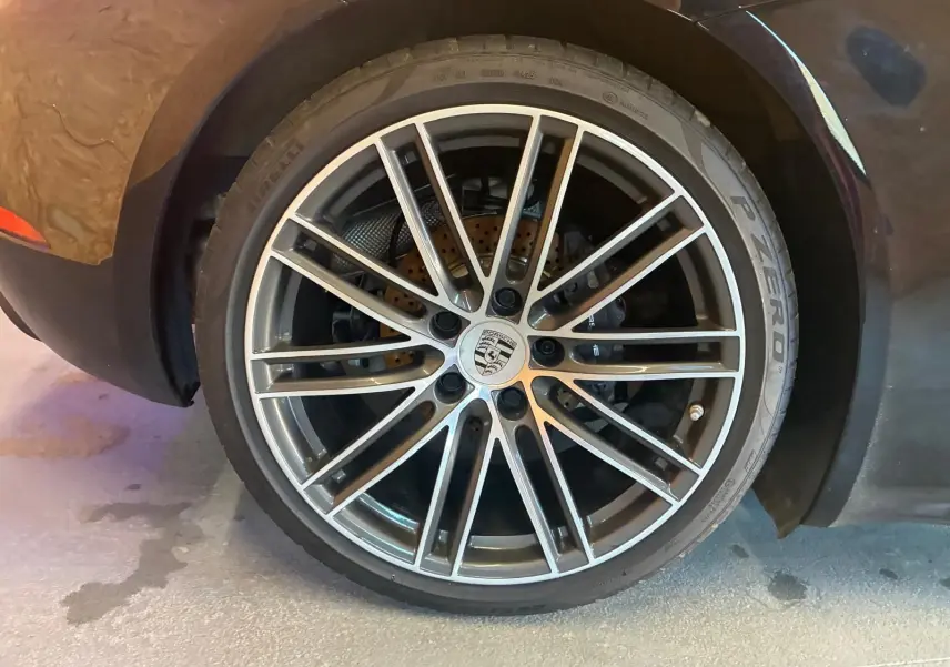 Gros plan sur la jante alliage argentée et le pneu Pirelli P Zero d'une Porsche 718 Boxster noire.