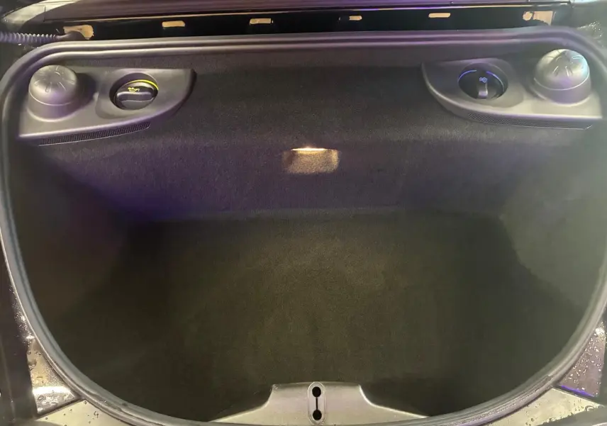 Vue plongeante sur le coffre avant noir de la Porsche 718 Boxster 2.0 300 essence, avec ouverture et compartiments latéraux visibles.