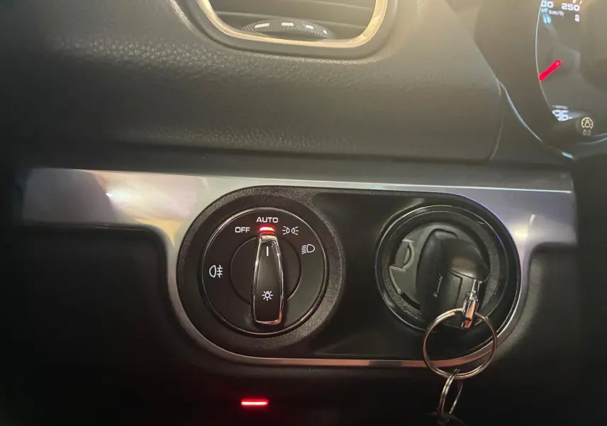 Détail du tableau de bord noir de la Porsche 718 Boxster 2.0 300 de 2018, avec commande des phares en position auto et clé insérée.