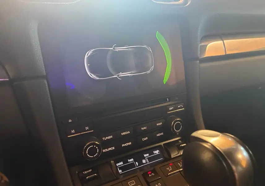 Vue rapprochée de la console centrale de la Porsche 718 Boxster noire, affichant l’écran multimédia et le levier de vitesse automatique.