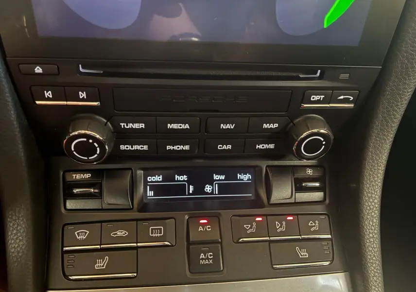 Gros plan sur la console centrale noire de la Porsche 718 Boxster 2.0 300 de 2018, montrant les commandes climatisation et multimédia.