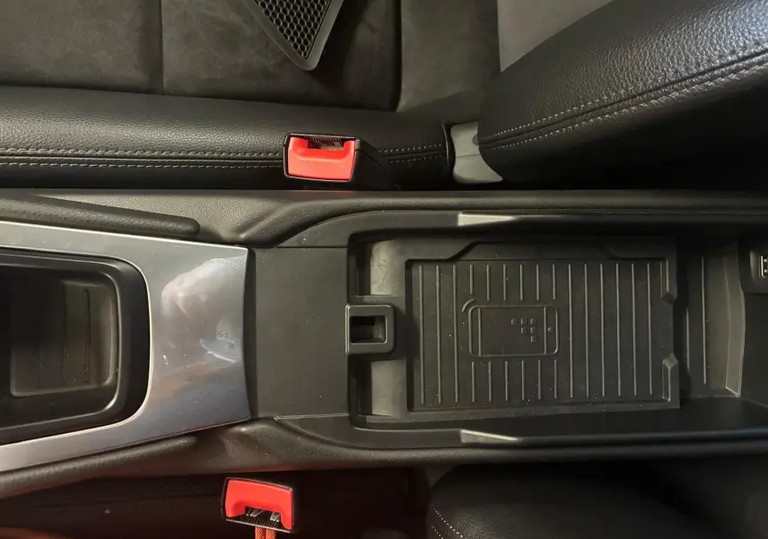 Vue plongeante sur la console centrale noire de la Porsche 718 Boxster 2.0 300, avec détails des ceintures rouges et rangement central.
