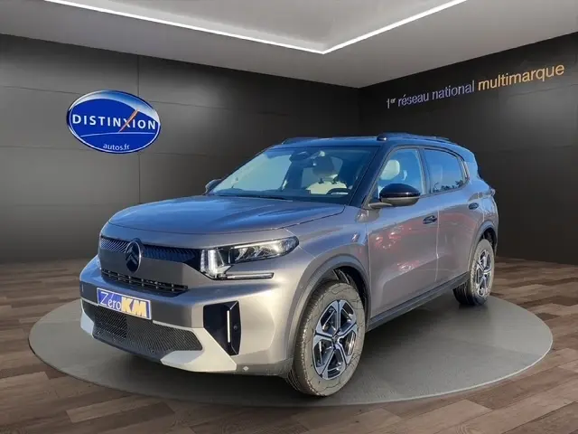 Vue 3/4 avant d'un Citroën C3 Aircross gris foncé avec jantes distinctives et toit noir en showroom.