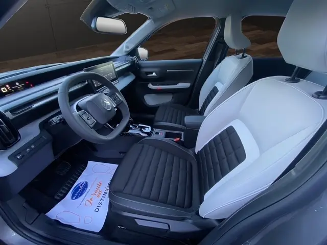 Vue intérieure côté conducteur de la Citroën C3 Aircross hybride 2026, sièges bicolores noir et blanc, tableau de bord moderne.