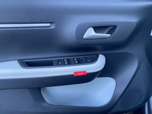 Gros plan sur la porte intérieure côté conducteur du Citroën C3 Aircross gris foncé, avec commande des vitres et étiquette rouge "be cool".
