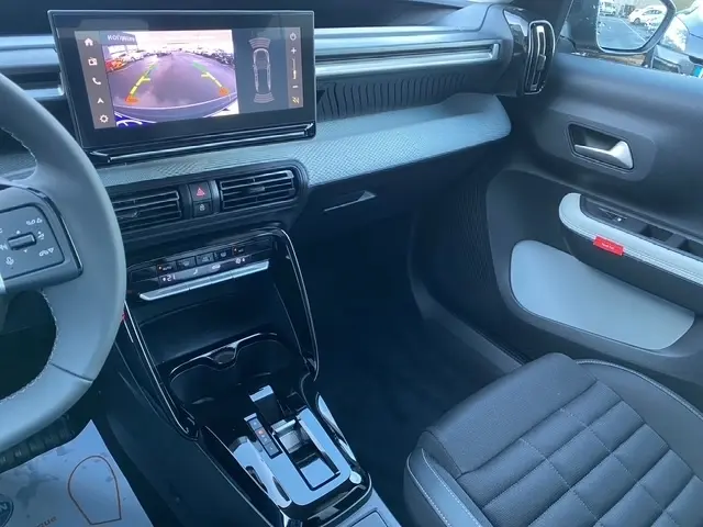 Intérieur du Citroën C3 Aircross hybride gris foncé, vue côté passager avec écran tactile et console centrale brillante.
