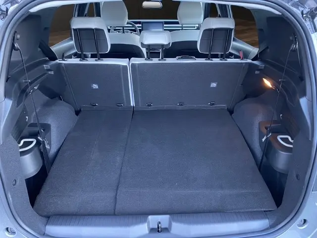 Vue depuis l'arrière du coffre du Citroën C3 Aircross gris foncé avec banquette arrière rabattue et sièges blancs visibles.