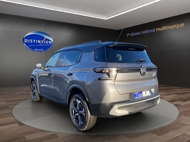 Vue 3/4 arrière droite d’un Citroën C3 Aircross gris foncé avec toit noir et jantes spécifiques en concession.
