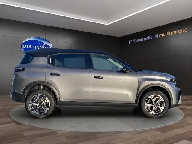 Vue de profil droit du Citroën C3 Aircross hybride gris foncé, avec jantes distinctives et toit noir contrasté.
