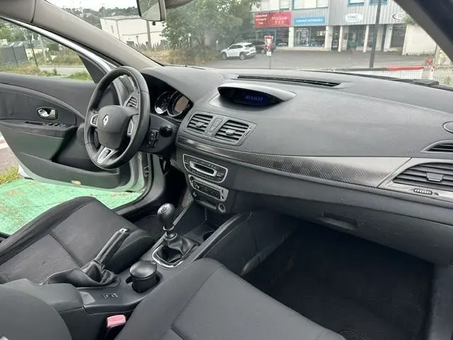 Intérieur avant de la Renault Mégane 3 gris, vue côté conducteur montrant tableau de bord, volant et boîte manuelle.