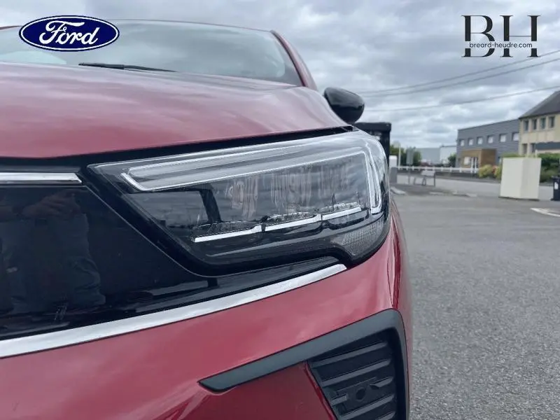Gros plan sur le phare avant droit rouge Kardio métallisé de l'Opel Crossland 2023 avec détails noirs et chrome.