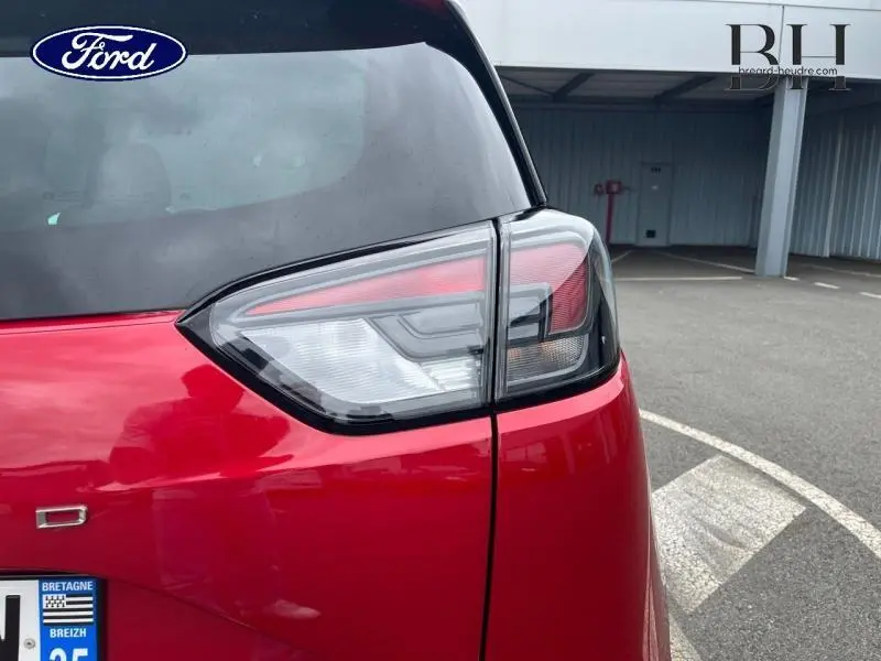 Gros plan sur le feu arrière droit d’un Opel Crossland 2023 rouge Kardio métallisé en stationnement extérieur.