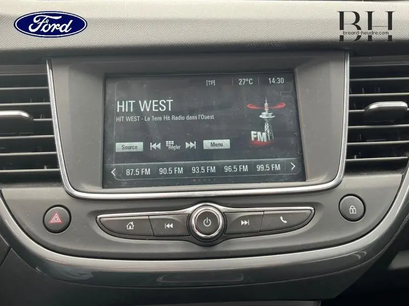 Écran tactile central de l’Opel Crossland rouge Kardio, affichant la radio FM avec commandes intégrées.