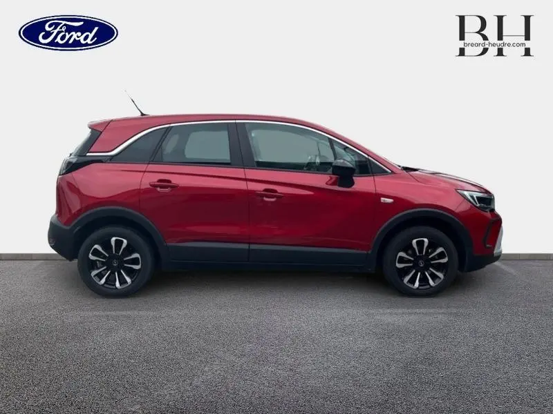Profil latéral droit d'un Opel Crossland rouge Kardio métallisé avec jantes alliage et toit blanc contrasté.