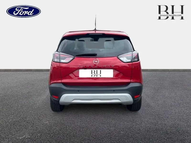 Vue arrière d'un Opel Crossland rouge Kardio métallisé 2023 avec becquet et pare-chocs gris contrastant.