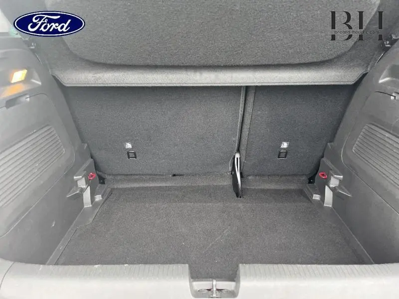 Coffre vide vu de face d'un Opel Crossland 2023 rouge Kardio métallisé avec intérieur noir et banquette rabattue.