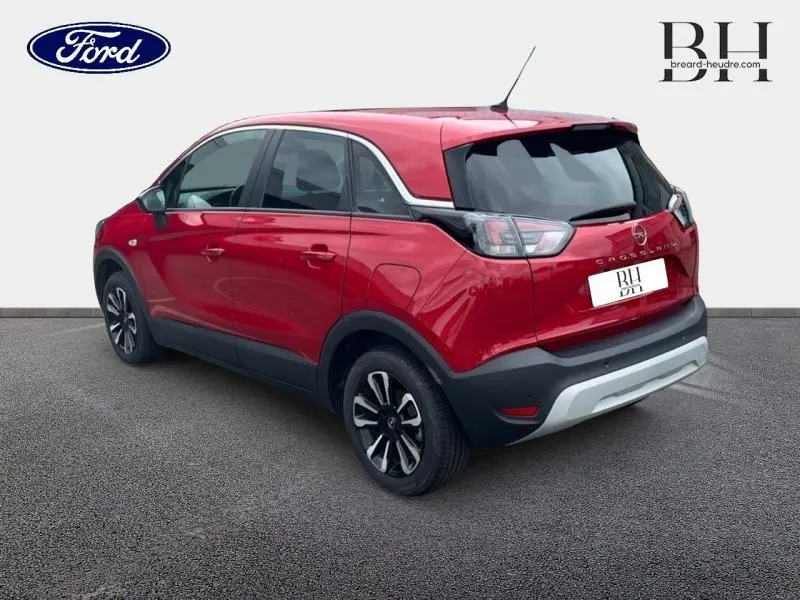 Vue 3/4 arrière droite d’un Opel Crossland rouge Kardio métallisé avec jantes alu et vitres arrière surteintées.