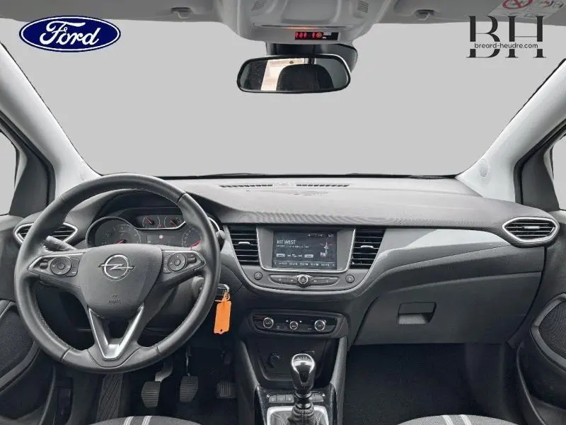 Vue intérieure avant de l’Opel Crossland 2023, tableau de bord noir avec volant cuir multifonction et écran tactile central.