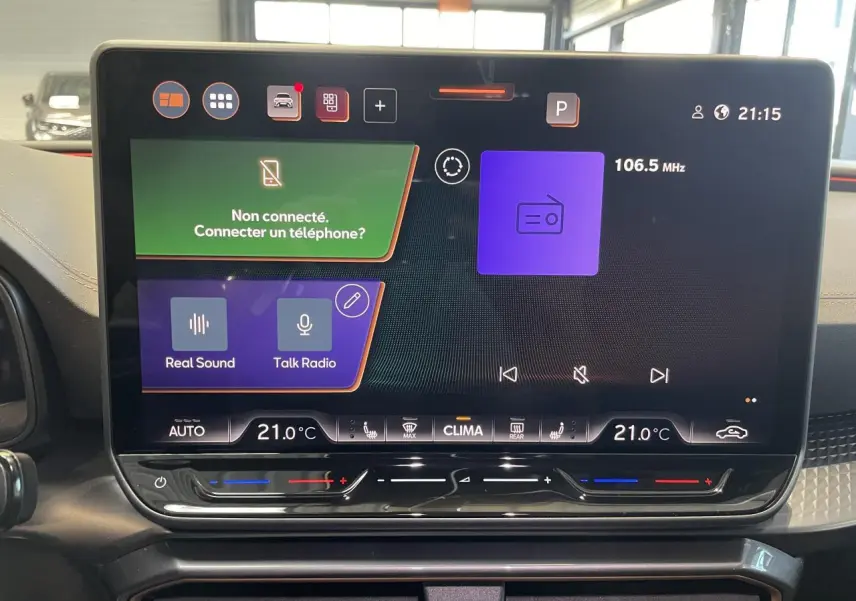 Écran tactile HD 12,9'' du tableau de bord du CUPRA Leon 2026, affichant la radio et la climatisation à 21°C.
