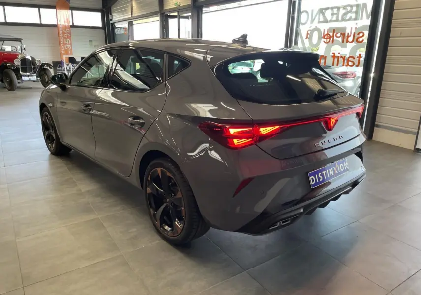 Vue 3/4 arrière droite d'une CUPRA Leon gris Graphène avec feux arrière Tri-LED et jantes alliage 18'' cuivrées.