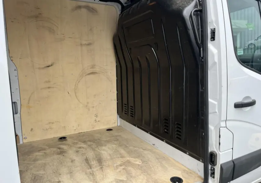 Vue intérieure de la zone de chargement du Renault Master blanc avec plancher et protection latérale en bois.