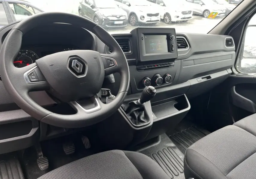 Vue intérieure côté conducteur du Renault Master 2023 avec volant, tableau de bord noir et levier de vitesses manuel.