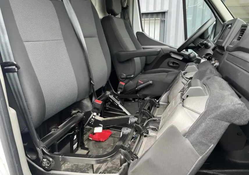 Vue intérieure côté passager du Renault Master blanc 2023, montrant la banquette rabattue et les sièges en tissu gris.