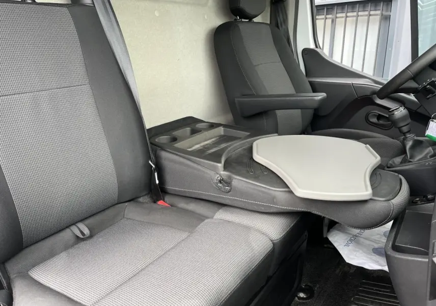Intérieur du Renault Master 2023, vue côté droit sur banquette 2 places avec tablette rotative et siège conducteur noir.