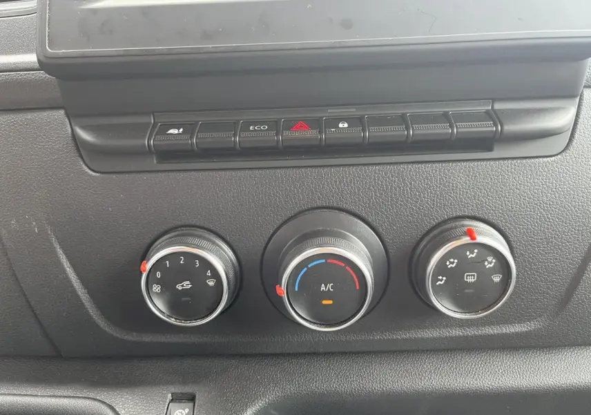 Commandes de climatisation manuelle avec trois molettes et boutons de fonction sur tableau de bord noir du Renault Master blanc 2023.