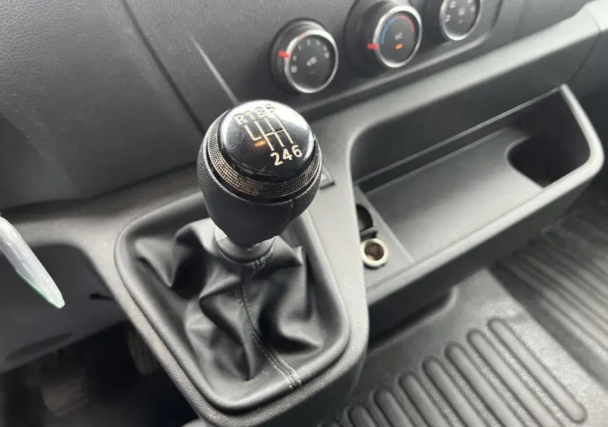Gros plan sur le levier de vitesses manuel noir du Renault Master 2023 avec commandes de climatisation en arrière-plan.