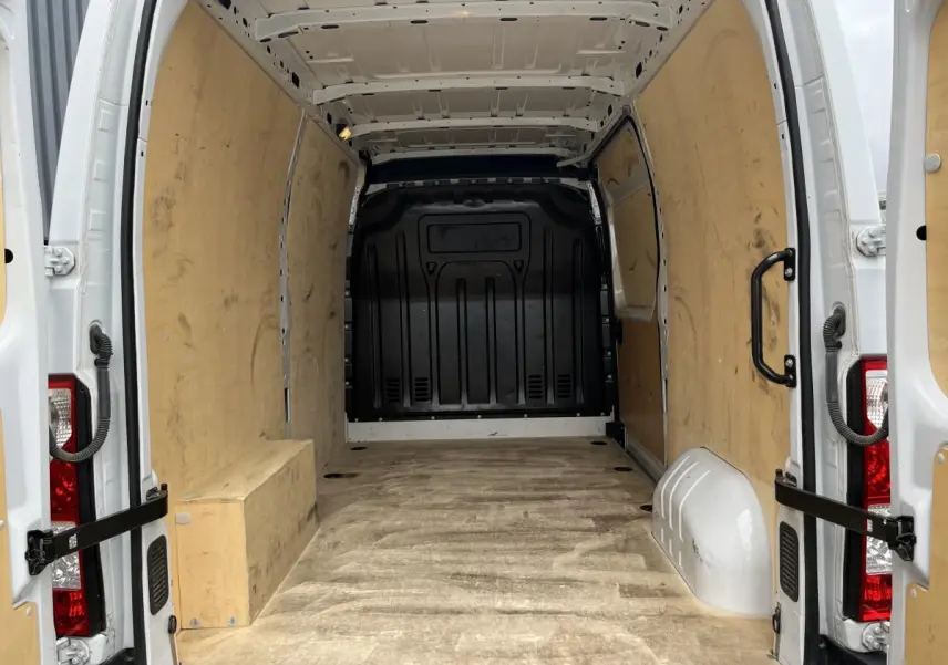 Intérieur du Renault Master blanc vu de l'arrière, montrant la zone de chargement avec plancher et protections latérales en bois.