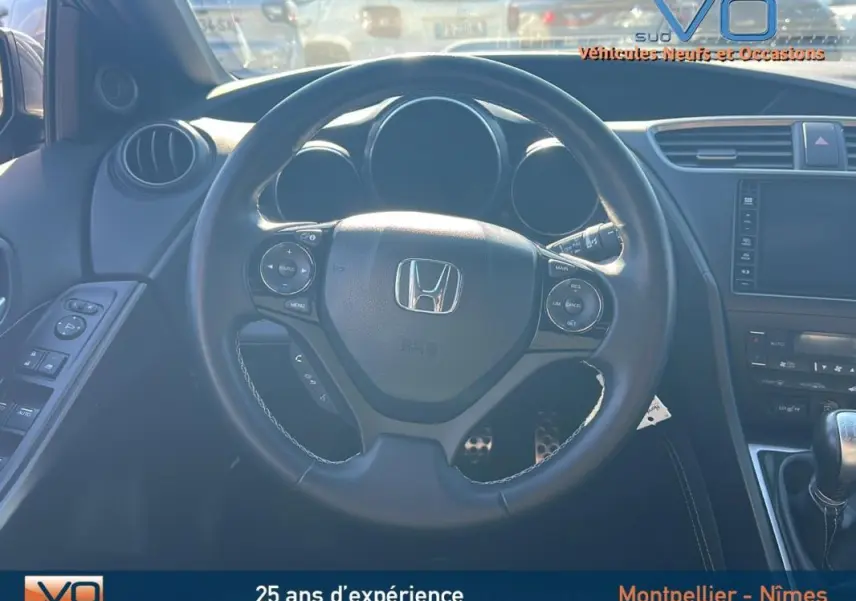 Vue intérieure centrée sur le volant multifonction d'une Honda Civic gris, avec tableau de bord et commandes visibles.