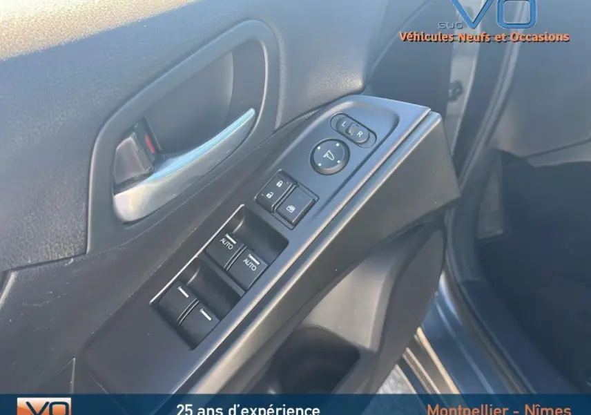 Gros plan sur la commande des vitres électriques et rétroviseurs côté conducteur d'une Honda Civic gris 2015.