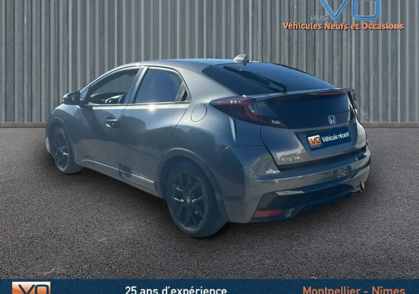 Vue 3/4 arrière droite d'une Honda Civic gris métallisé avec vitres surteintées et jantes alliage noires.