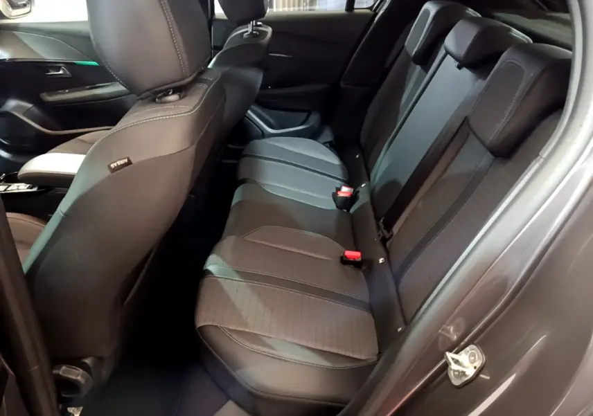 Vue intérieure côté droit sur la banquette arrière noire de la Peugeot 208 gris foncé avec appuie-têtes et ceintures visibles.