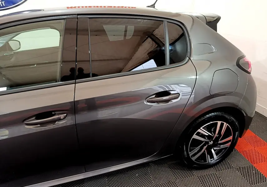 Vue latérale droite d'une Peugeot 208 gris foncé mettant en valeur ses jantes alliage modernes et ses lignes épurées.