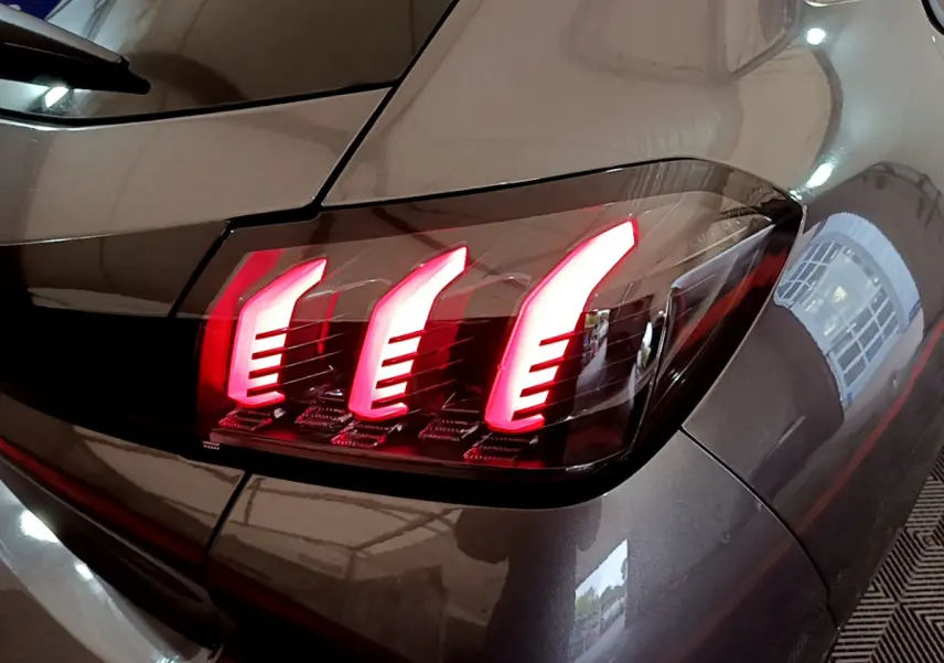 Gros plan sur le feu arrière droit allumé d'une Peugeot 208 gris foncé, version PureTech 100 S&S EAT8 Allure Pack 2022.