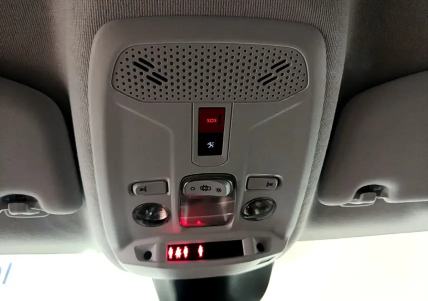 Vue en contre-plongée du plafonnier gris clair avec bouton SOS et éclairages intégrés dans une Peugeot 208 gris foncé.
